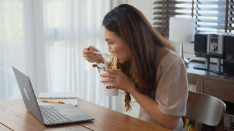 业务女人吃即时面条工作移动PC电脑