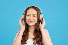 快乐亚洲十几岁的女孩听音乐首歌无线耳机球员技术放松音乐情人概念