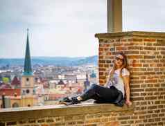 女孩坐在砖墙欣赏全景布拉格