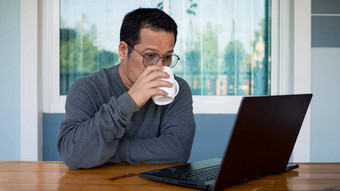 亚洲但穿长袖子眼镜喝咖啡坐着首页工作电脑木表格工作首页概念