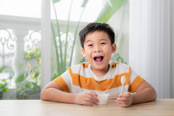 可爱的男孩吃酸奶白色酸奶容器的地方广告