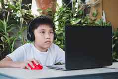 亚洲男孩穿无线耳机移动PC电脑研究在线
