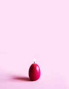 传统的复活节装饰集团明亮的燃烧石蜡蜡烛形状色彩斑斓的鸡蛋粉红色的背景