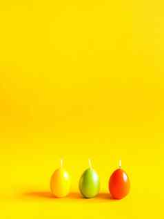 传统的复活节装饰集团明亮的燃烧石蜡蜡烛形状色彩斑斓的鸡蛋黄色的背景