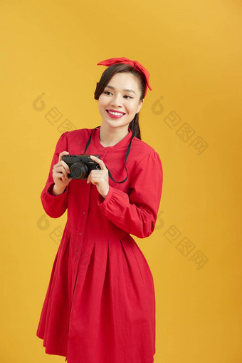 快乐的年轻的亚洲女人数字相机准备好了享受旅行黄色的孤立的背景