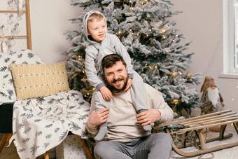 假期圣诞节英俊的父亲玩小可爱的儿子装饰一年树首页