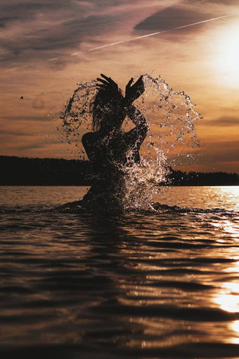 年轻的模型游泳海日落时间有吸引力的轮廓喷雾