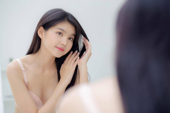美丽的年轻的亚洲女人微笑镜子触摸头发房间化妆品卫生头发护理美亚洲女孩快乐发型治疗首页生活方式化妆概念