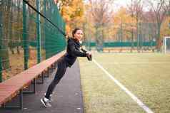 女孩运动员培训体育运动地面混合比赛年轻的成人女人锻炼悬架系统健康的生活方式伸展运动在户外操场上