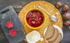 红色的传统的俄罗斯ucrainian罗宋汤甜菜根汤酸奶油大蒜调味料黄色的陶瓷杯柳条盘垫纸背景