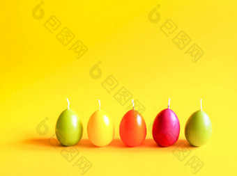 传统的复活节装饰集团明亮的燃烧石蜡蜡烛形状色彩斑斓的鸡蛋黄色的背景