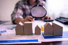 真正的房地产房子评估计算器持有放大玻璃模型木房子财产估值评估搜索住房概念