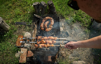 烧烤<strong>肉</strong>香肠德国碎<strong>肉</strong>香肠烧烤炉篦后院男人。准备烤羊<strong>肉</strong>串希什烤<strong>肉</strong>串木炭烤<strong>肉</strong>金属串<strong>肉</strong>扦户外烧烤聚会，派对野餐食物关闭拍摄