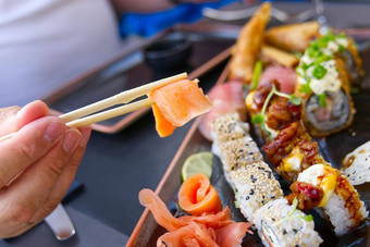 男人。吃大马哈鱼生鱼片日本餐厅男人。持有筷子吃新鲜的大马哈鱼生鱼片