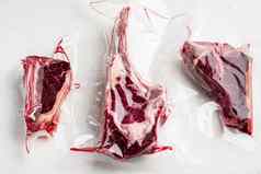 干岁的牛排真空肉产品塑料包战斧骨俱乐部牛排削减白色石头背景