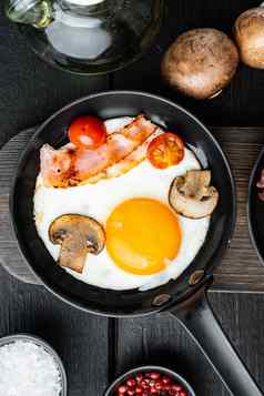 炸鸡蛋樱桃西红柿面包早餐投铁煎锅黑色的木表格背景前视图平躺