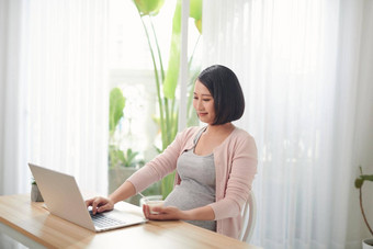 怀孕了女人坐着表格桌子上健康的早餐移动PC