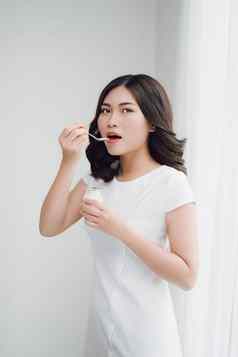 肖像年轻的亚洲女人首页吃酸奶
