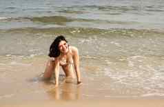 年轻的女人摆姿势跪着沙子海