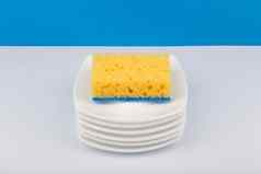 洗碗概念高角视图清洁海绵桩清洁碟子白色表格蓝色的背景