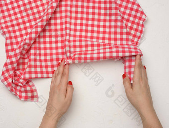 女手持有皱巴巴的white-red网纹纺织厨房餐巾白色表格