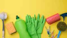 橡胶绿色手套清洁红色的垃圾塑料袋卷塑料瓶洗涤剂刷黄色的背景