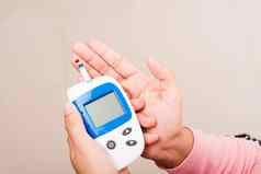 女人测量葡萄糖测试水平检查血手指glucometer