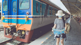 年轻的女旅游穿面具走火车站旅游地图旅行信息概念正常的旅行旅游