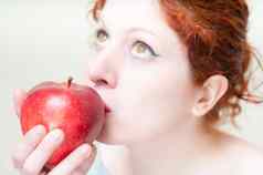 美丽的红色的头发嘴唇女孩接吻苹果