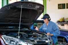 亚洲汽车机械师蓝色的统一的电子工具检查车部分引擎罩车库