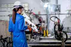 回来工厂工人女人持有控制器控制金属焊接机器人机工作工作场所区域工业技术支持系统工作员工概念