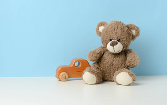 可爱的棕色（的）泰迪熊坐在白色<strong>表</strong>格木孩子们的玩具车<strong>蓝色</strong>的背景