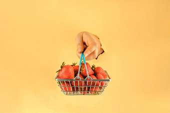 女孩持有手购物篮子红色的成熟的草莓女人的手撕裂纸在线购物概念