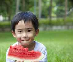 可爱的亚洲男孩吃西瓜草