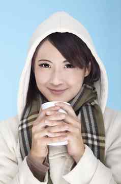 年轻的女人穿冬天服装持有咖啡杯