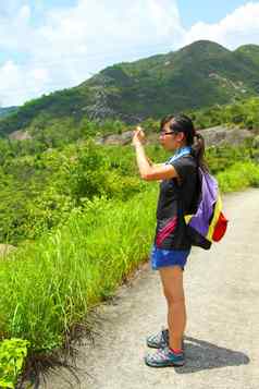 年轻的女人背包徒步旅行采取照片