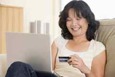 女人生活房间移动PC持有信贷卡微笑