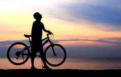 轮廓男人。骑自行车美丽的湖