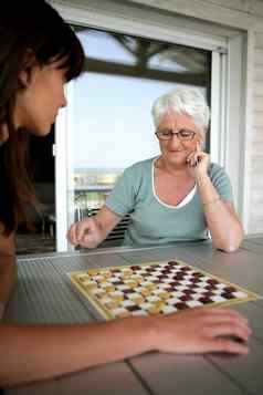 年轻的女人高级女人玩跳棋