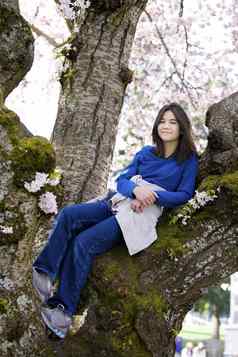 年轻的青少年女孩坐着樱桃树完整的布鲁姆