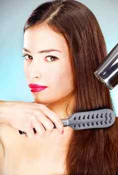 女人长头发持有打击干燥机梳子