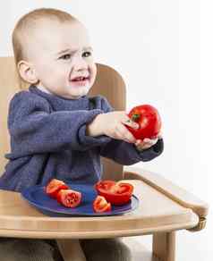 年轻的孩子吃西红柿高椅子