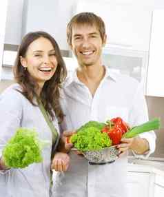 年轻的夫妇烹饪健康的食物饮食厨房