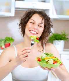 饮食美丽的年轻的女人吃蔬菜沙拉