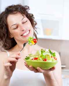 饮食美丽的年轻的女人吃蔬菜沙拉