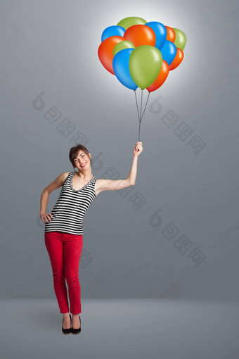 年轻的女人持有色彩斑斓的气球