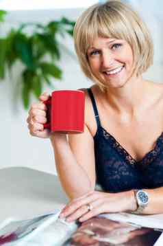 肖像放松女人持有红色的咖啡杯子