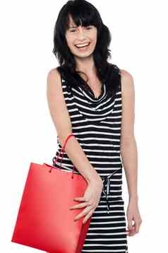 欢乐的浅黑肤色的女人摆姿势红色的购物袋
