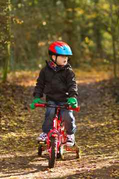 男孩骑自行车林地小道