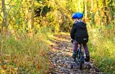 男孩骑自行车林地小道